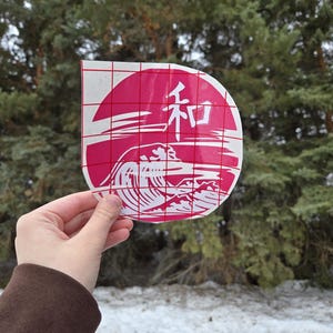 May include: A white vinyl sticker with a red background and a wave design. The sticker has the Japanese word "和" (wa) for peace in the centre.