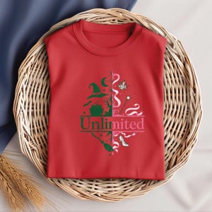 May include: A red t-shirt with a graphic design featuring witch-themed elements. The design includes a witch hat, cauldron, broom, and high heel. The word "Unlimited" is printed in green and pink.