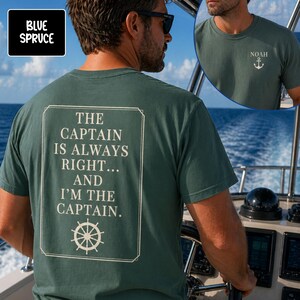 Pu&ograve; includere: Una maglietta blu abete con la scritta "THE CAPTAIN IS ALWAYS RIGHT... AND I'M THE CAPTAIN" in un riquadro bianco. La maglietta presenta anche una grafica del timone. Un'immagine pi&ugrave; piccola mostra una maglietta con il nome "NOAH" e un'ancora.