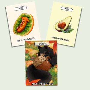 Puede incluir: Tres cartas ilustradas que representan alimentos. Una muestra un perrito caliente, otra un aguacate y la tercera una ardilla negra con una bellota. Cada carta tiene la palabra "FOOD" en la parte superior y texto de juego en la parte inferior.