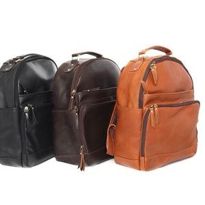 May include: Three leather backpacks in different colors: black, brown, and tan. The backpacks have multiple pockets and zippers.