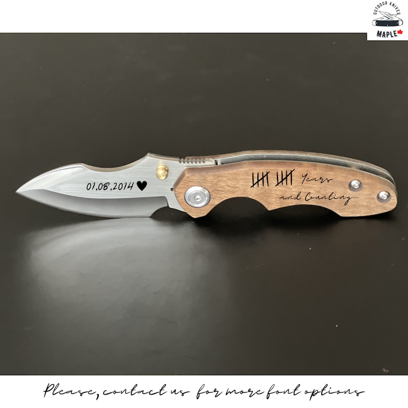 May include: A brown wooden handled pocket knife with a silver blade. The handle is engraved with the date "01.08.2014" and a heart symbol. The blade is engraved with "IIII IIII Years and Counting".