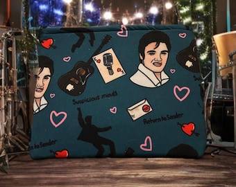 Può includere: Una pochette con cerniera blu turchese con un motivo ripetuto di un cartone animato di Elvis Presley, una chitarra, un microfono, una carta da gioco, un cuore e il testo "Suspicious Minds" e "Return to Sender".