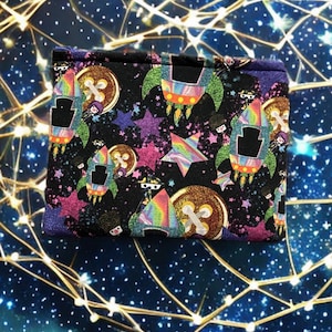 May include: A black zippered pouch with a colourful space-themed print. The print features rockets, stars, and planets.