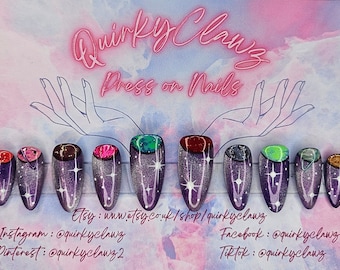 Puede incluir: Un conjunto de diez uñas postizas con temática de galaxia. Cada uña tiene un color y diseño diferente, incluyendo rojo, marrón, rosa, verde y gris. Las uñas están decoradas con purpurina y estrellas. La imagen también incluye el texto "Quirky Clawz Press on Nails" y las cuentas de redes sociales del vendedor.