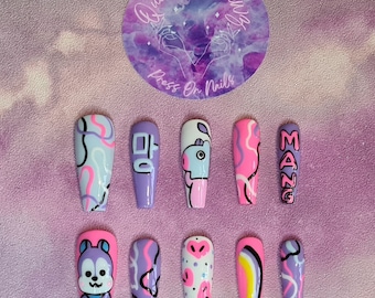 Puede incluir: Conjunto de diez uñas postizas largas, de color morado y rosa, con varios diseños. Los diseños incluyen un personaje de dibujos animados, la palabra coreana "마" (que significa "ma") y la palabra "MAZE".