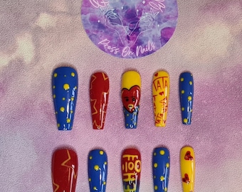 Puede incluir: Conjunto de diez uñas postizas con base azul y amarilla y varios diseños. Los diseños incluyen un corazón rojo con un oso de dibujos animados, estrellas amarillas y el texto "HEIZE 100".