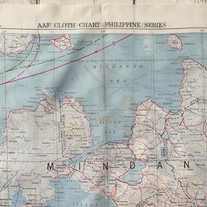 May include: A vintage cloth chart of the Philippine Series, featuring detailed geographical information. The map displays various islands, cities, and bodies of water, with text labels and contour lines. The color palette includes shades of blue, green, and red.