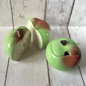 以下が含まれることがあります： リンゴの形をしたセラミック製のキッチンセット。塩入れ、コショウ入れ、蓋付きの砂糖入れが含まれています。緑と茶色の配色で、光沢のある仕上がりです。塩入れの上部には穴があります。