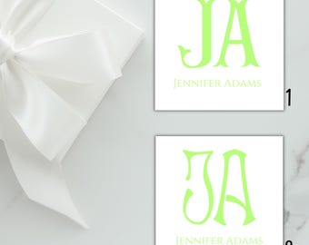 May include: Two white cards with the initials "JA" in a bright green, along with the name "Jennifer Adams" below. A white gift box with a large white bow is in the upper left corner.