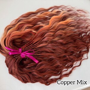 May include: A bundle of copper-colored wavy hair extensions, tied with a bright pink ribbon. The hair has a mix of shades, including red, orange, and light brown. The text "Copper Mix" is visible in the bottom right corner.