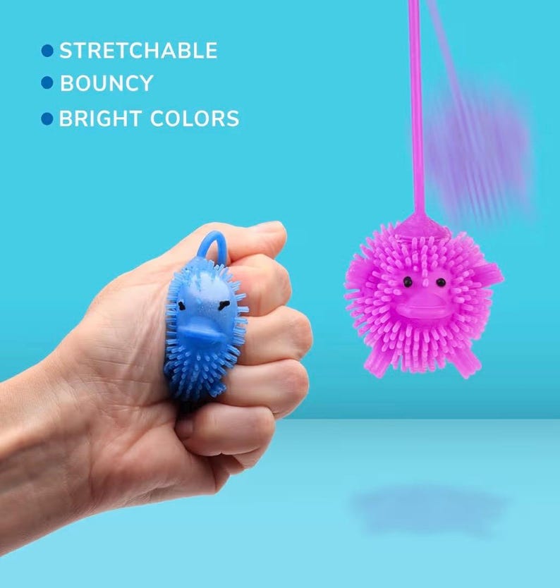 May include: A hand holds a blue, spiky toy shaped like a duck. A pink, spiky ball toy with a face is suspended by a string. Text on the left reads: Stretchable, Bouncy, Bright Colors. The background is a light blue.