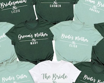 May include: A collection of ten short-sleeved t-shirts in dark green, light green, and white. Each shirt features white text with titles like Bridesmaid, Maid of Honor, Team Bride, Bride Squad, Groom's Mother, Bride's Mother, and The Bride.
