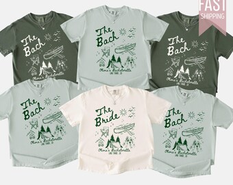 Peut inclure: Plusieurs t-shirts de couleurs variées, dont du vert et du blanc. Chaque t-shirt affiche l'inscription "The Bach" ou "The Bride" en vert, avec des illustrations sur le thème du camping. Les t-shirts sont pour un enterrement de vie de jeune fille.