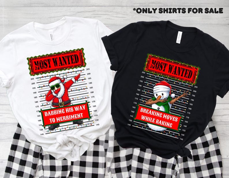 May include: Two t-shirts, one white and one black, with Christmas-themed graphics. The white shirt features Santa dabbing with the text "Most Wanted" and "Dabbing His Way to Merriment." The black shirt shows a snowman dabbing with the text "Breaking Moves While Baking."