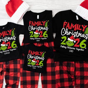 May include: A set of black short-sleeved t-shirts and red and black plaid pajama pants with matching red and white Santa hats. The shirts feature a graphic of a green character, the text Family Christmas 2026, and Making Memories Together.
