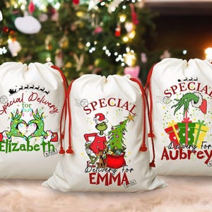 May include: Three white Christmas gift bags with red drawstrings. Each bag features a Grinch-themed design and the words "Special Delivery" with a name. One bag has a Grinch hand heart, another has the Grinch with a Christmas tree, and the last has the Grinch with gifts.