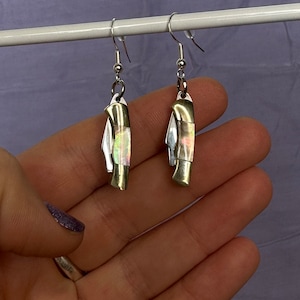 Puede incluir: Un par de pendientes de plata con forma de navaja de bolsillo con incrustaciones de nácar iridiscente.