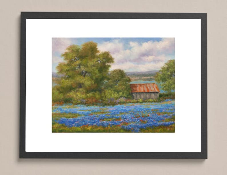 May include: A painting of a rustic wooden barn with a red metal roof, nestled in a field of bluebonnet wildflowers. The barn is surrounded by green trees and a blue sky with white clouds.