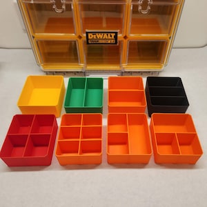 May include: A yellow and clear plastic storage organiser with the text "DEWALT TOUGH SYSTEM 2.0". The image shows several colourful storage bins in yellow, green, orange, red, and black.