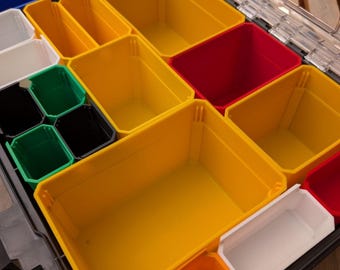 Può includere: Un organizer multicolore con contenitori in plastica di varie dimensioni. I contenitori sono gialli, rossi, bianchi, verdi, neri e blu. L'organizer è progettato per contenere piccoli oggetti e strumenti.