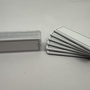 May include: A white ceramic mug with a black handle and the text "But First, Coffee" in a black, bold font. The mug is sitting on a white surface. The mug is approximately 4 inches tall.