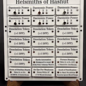 May include: A white game board with the text "Helsmiths of Hashut" and various game tokens. The tokens are labeled "Daemonic Power" and "Desolation Token" with additional game-related text. The board is supported by a wooden stand.