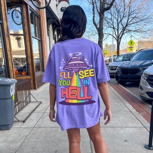 Może przedstawiać: Fioletowy T-shirt z grafiką UFO i tekstem "I'll see you in hell".