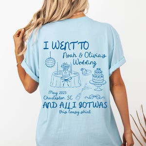 May include: Light blue t-shirt with a blue graphic that says "I went to Noah & Olivia's Wedding May 2025 Charleston, SC and all I got was this lousy shirt". The graphic also includes a wedding cake, a table setting, and a disco ball.