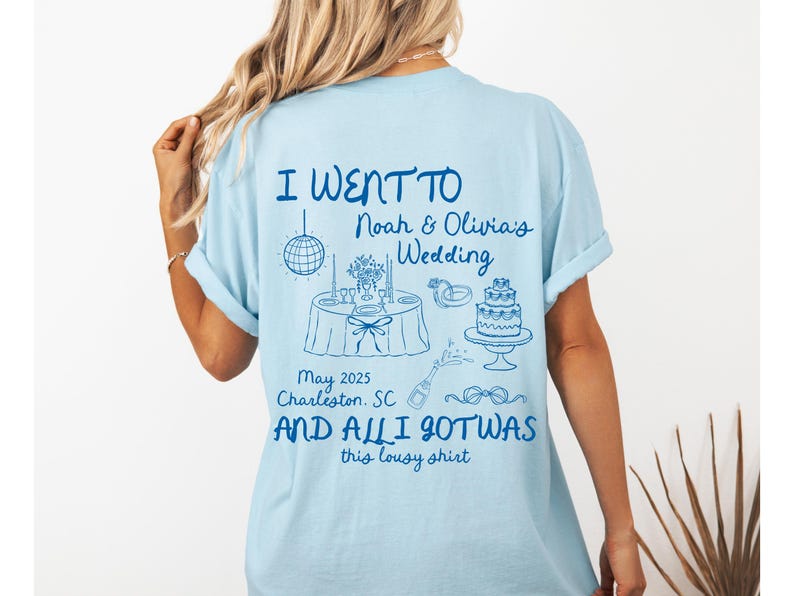 May include: Light blue t-shirt with a blue graphic that says "I went to Noah & Olivia's Wedding May 2025 Charleston, SC and all I got was this lousy shirt". The graphic also includes a wedding cake, a table setting, and a disco ball.