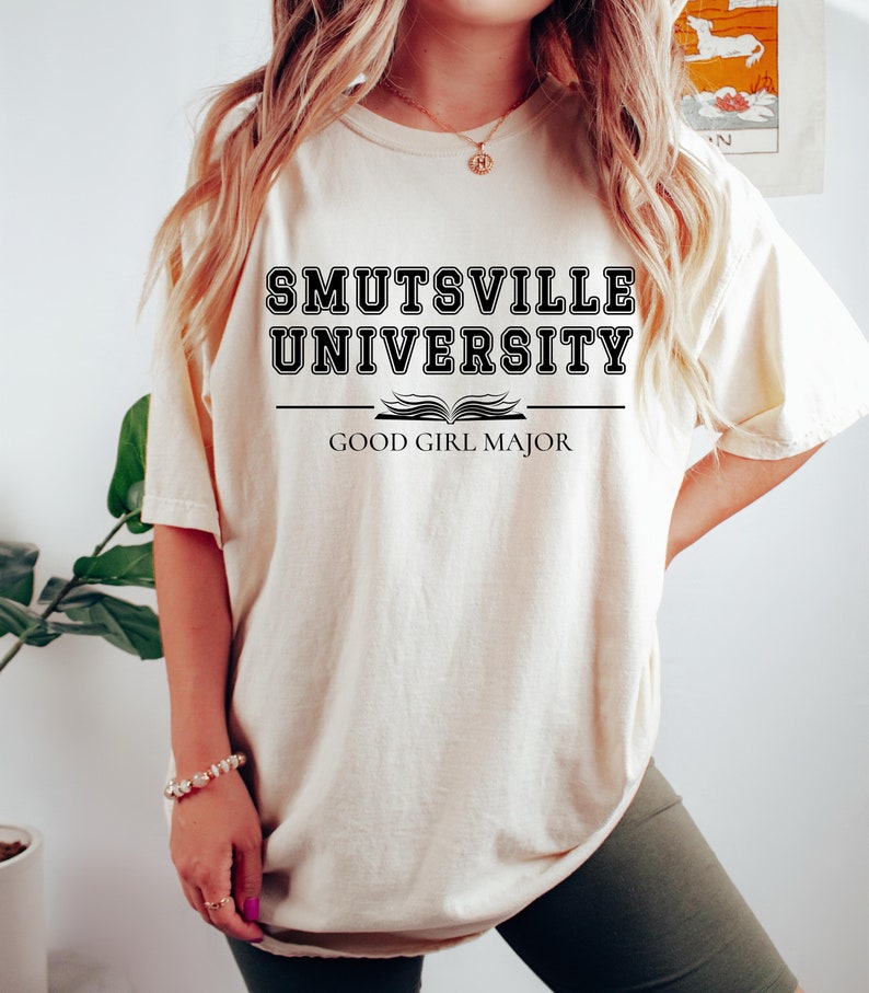 May include: An oversized white t-shirt with black text that reads "Smutsville University" with an open book graphic and the text "Good Girl Major" underneath.