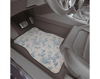 May include: A white car floor mat with a blue floral pattern. The mat is in the driver's side footwell of a car.