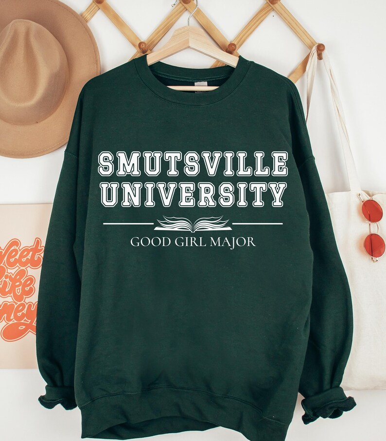 May include: A dark green sweatshirt with white text that reads "Smutsville University Good Girl Major".