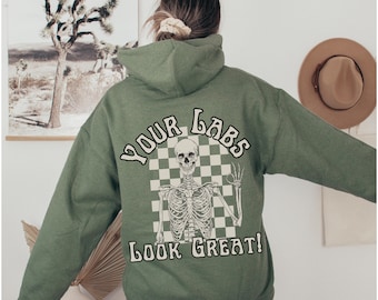 May include: Green hooded sweatshirt with a white skeleton graphic and the text "YOUR LABS LOOK GREAT!" on the back.
