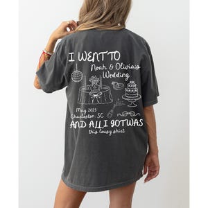 May include: A dark gray t-shirt with white text that reads "I went to Noah & Olivia's Wedding May 2025 Charleston, SC and all I got was this lousy shirt".