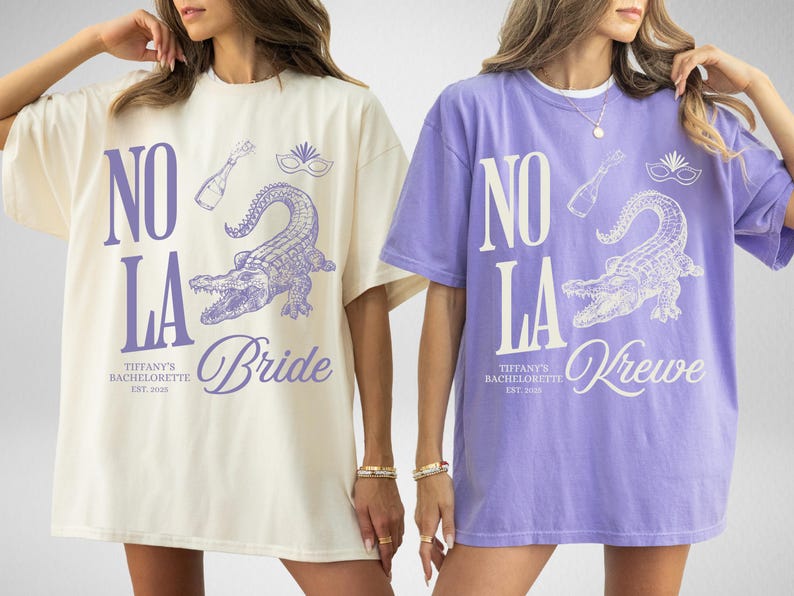 May include: Two oversized t-shirts, one cream and one lavender, featuring a purple alligator graphic with the text "NO LA" and "Bride" or "Krewe". The shirts are for Tiffany's Bachelorette, EST. 2020.