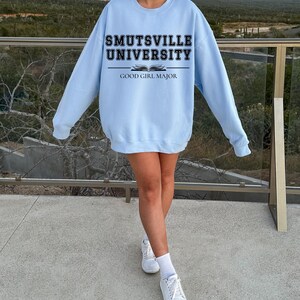 May include: A light blue sweatshirt with the text "Smutsville University" and "Good Girl Major" printed on the front.