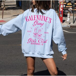 May include: Light blue sweatshirt with a pink graphic that says "Galentine's Gang Est. 2025 Girls Club Scottsdale, AZ"
