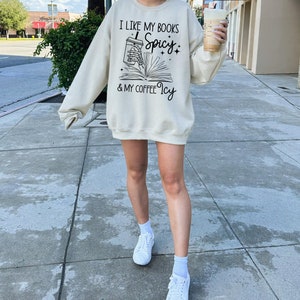 May include: A cream-coloured sweatshirt with a graphic print that says "I like my books spicy & my coffee icy". The graphic features a book with a coffee cup spilling out of it.