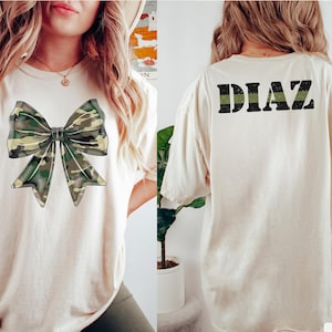 Benutzerdefinierte Armee Frau Shirt mit Namen, personalisierte Armee Solider Familie Shirt, stolze Militärfamilie Komfort Farben Green Line Camo Coquette Bow