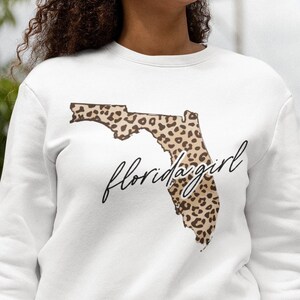May include: White sweatshirt with a leopard print outline of the state of Florida and the text "floridagirl" in black script.