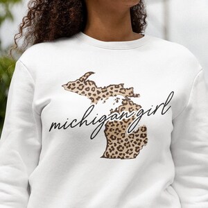 May include: White sweatshirt with a leopard print outline of the state of Michigan and the text "michigan girl" in black script.