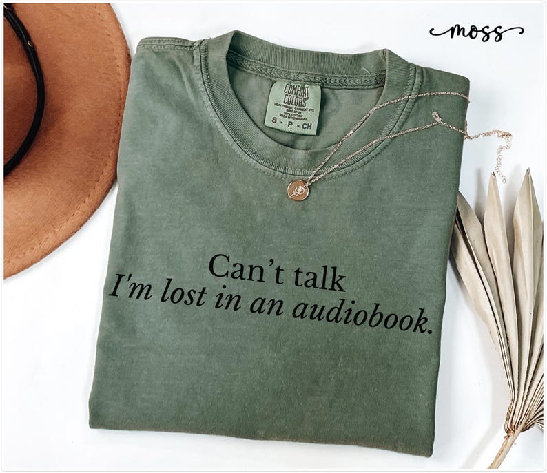 May include: A green t-shirt with the text "Can't talk I'm lost in an audiobook." printed in black.