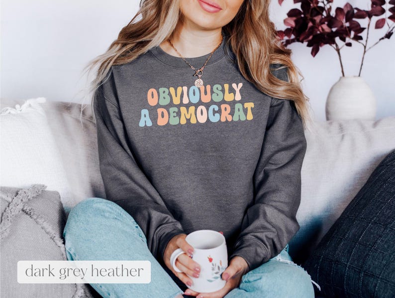 May include: A dark grey heather sweatshirt with the text "OBVIOUSLY A DEMOCRAT" in rainbow colors.