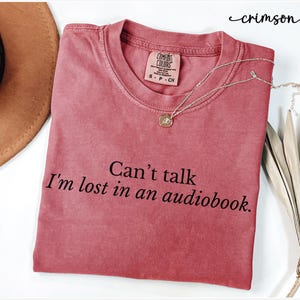 May include: Crimson red t-shirt with the text "Can't talk I'm lost in an audiobook."