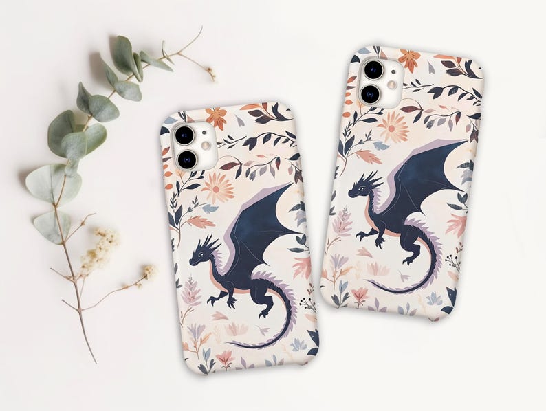 May include: Two phone cases with a floral pattern and a black dragon design. The cases are white with pink, blue, and yellow flowers.