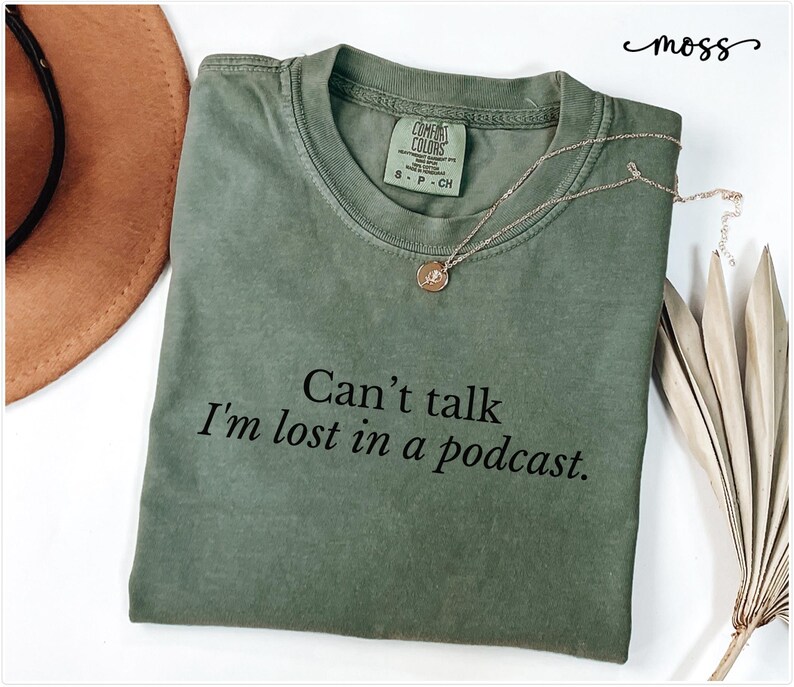 May include: A green t-shirt with the text "Can't talk I'm lost in a podcast." printed on it.
