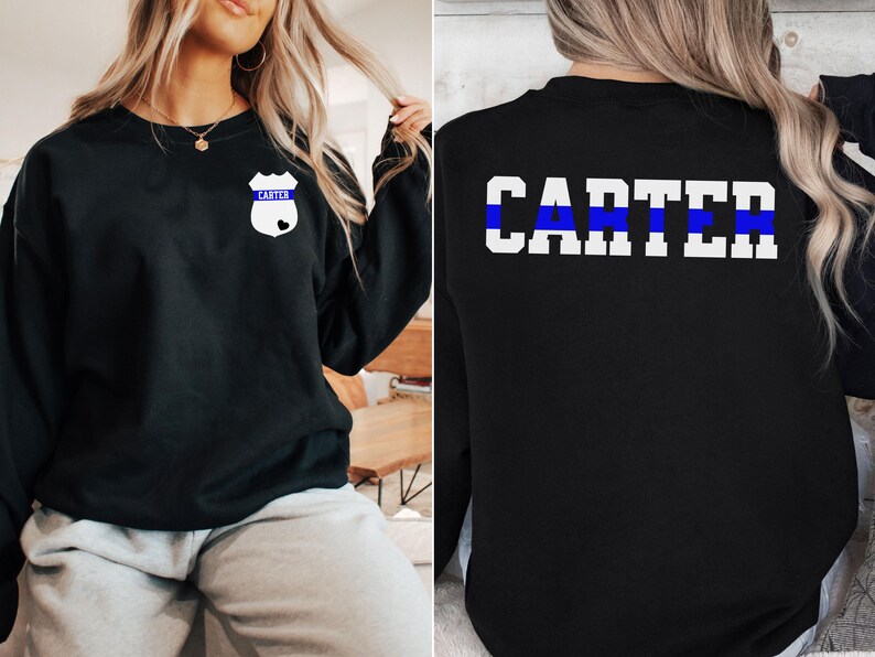 K&ouml;nnte beinhalten: Schwarzer Pullover mit einem blauen Streifen und dem Namen "CARTER" auf der R&uuml;ckseite. Die Vorderseite des Pullovers hat ein wei&szlig;es Abzeichen mit dem Namen "CARTER" und einem blauen Streifen.