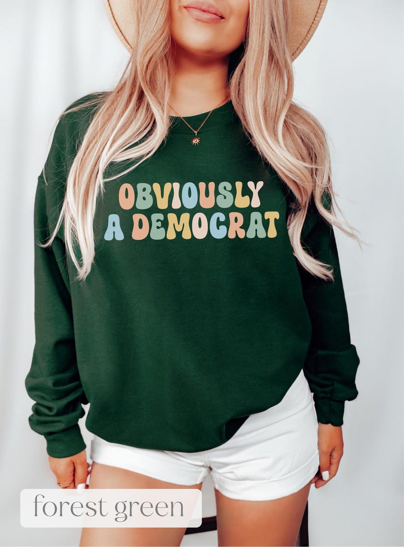 May include: A forest green sweatshirt with the text "OBVIOUSLY A DEMOCRAT" in colorful retro lettering.