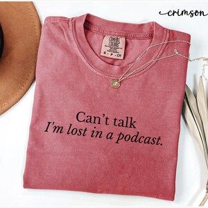 May include: Crimson red t-shirt with the text "Can't talk I'm lost in a podcast."